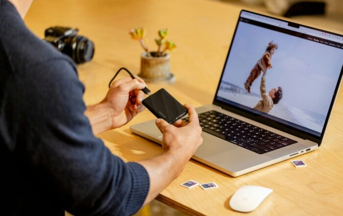 A man sitting at a table with a laptop and cell phone